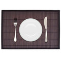 Dark brown bamboo placemat with plate and cutlery on a set dining table