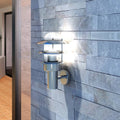 Casora stainless steel LED wall light mounted on a stone wall