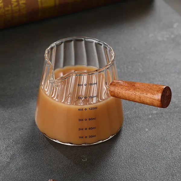 Clear glass milk cup with wooden handle on a table